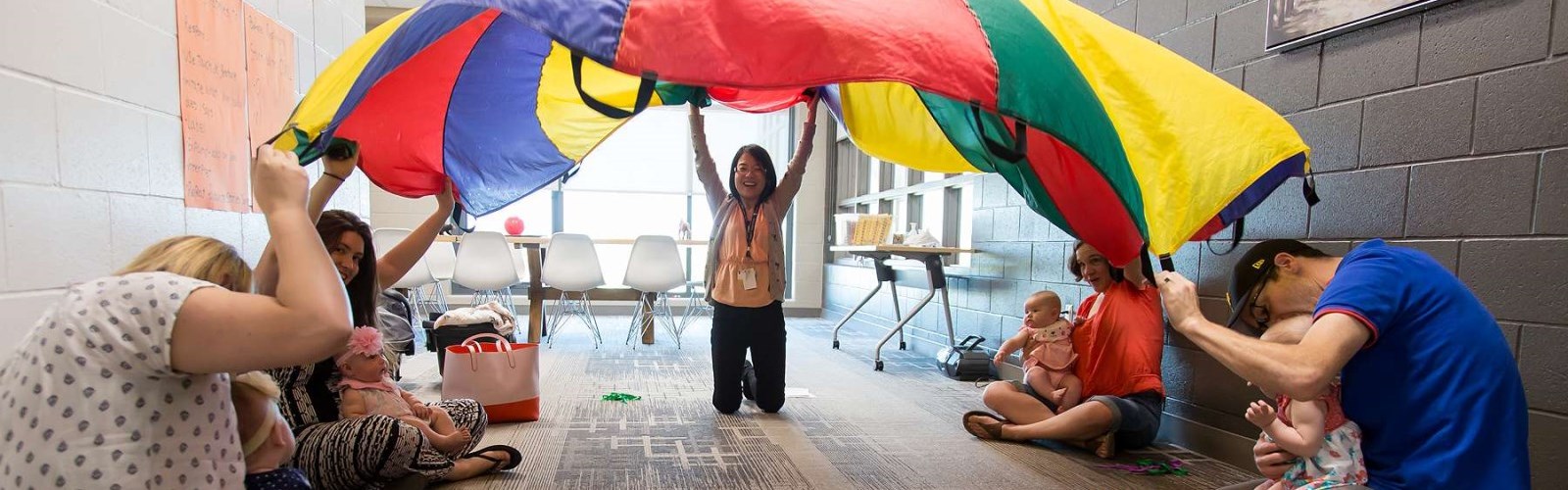 Parents and children playing with a coloured parachute